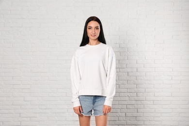 Photo of Portrait of young woman in sweater at brick wall. Mock up for design