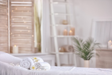 Photo of Towels and candles on massage table in modern spa salon. Place for relaxation