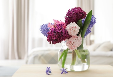 Beautiful hyacinths in glass vase on table indoors, space for text. Spring flowers