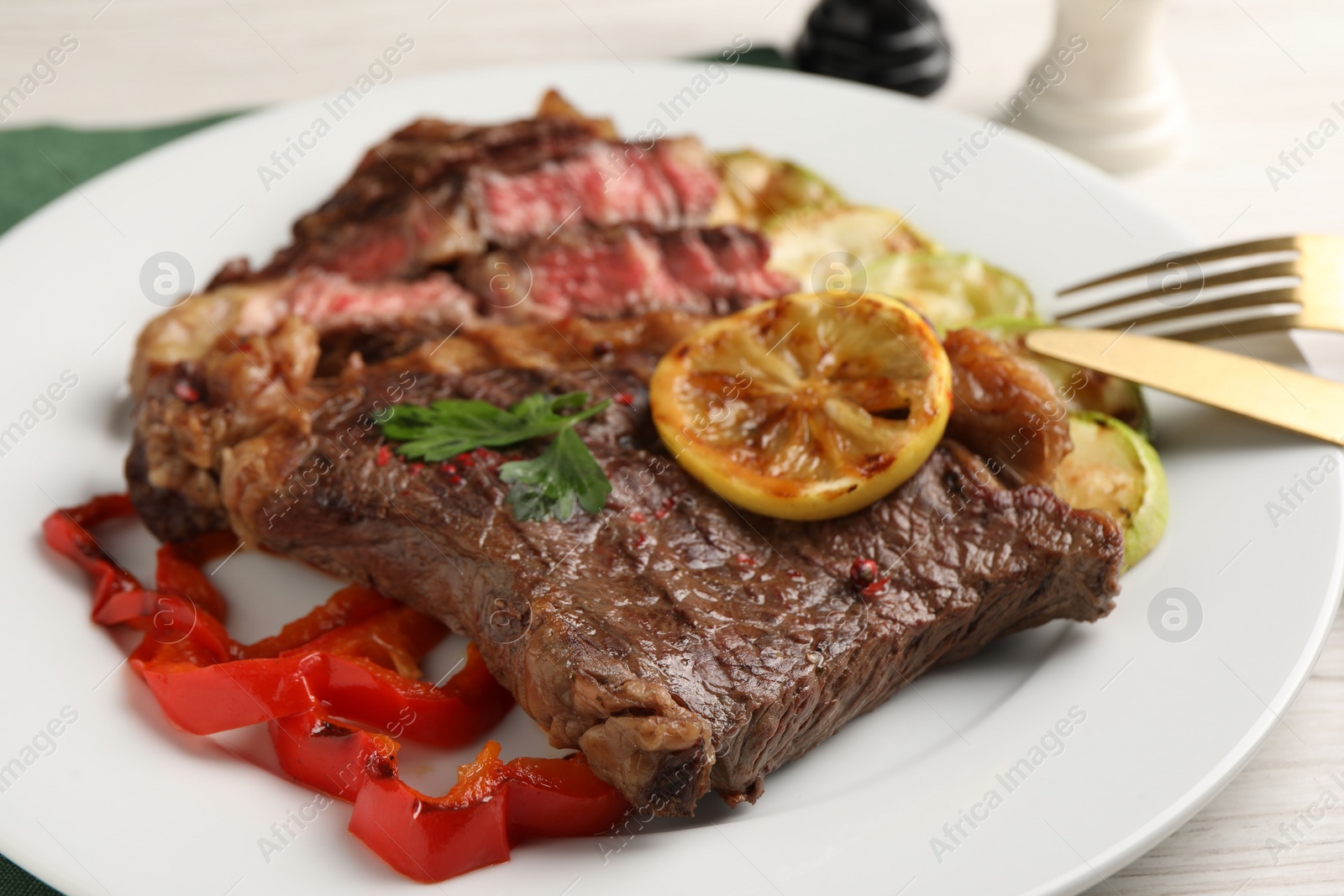 Photo of Delicious grilled beef steak and vegetables on table, closeup