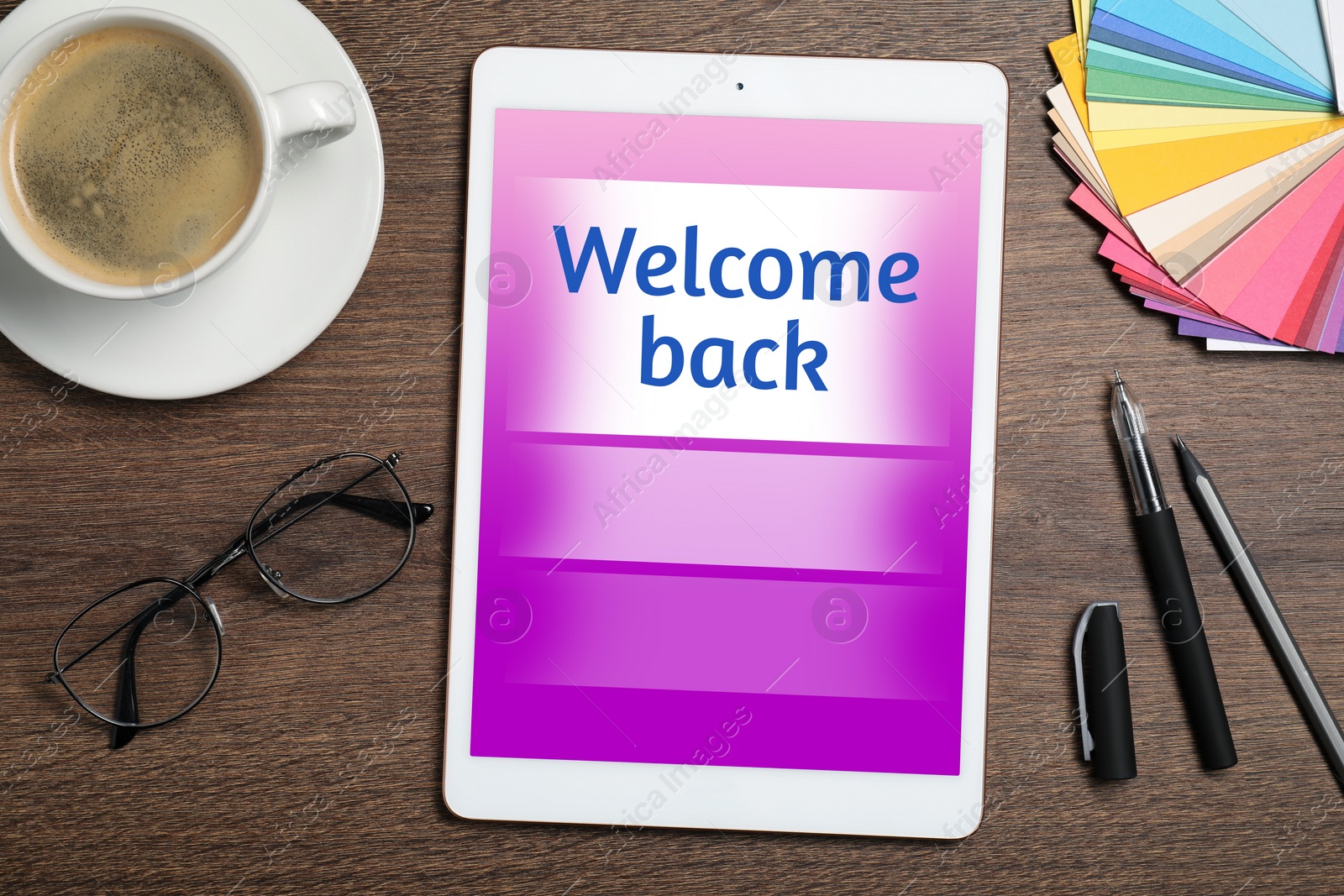 Image of Tablet with phrase Welcome Back on wooden table. Office desk with cup of coffee, flat lay