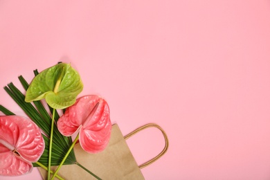 Stylish flat lay composition with shopping bag, tropical leaf and flowers on color background