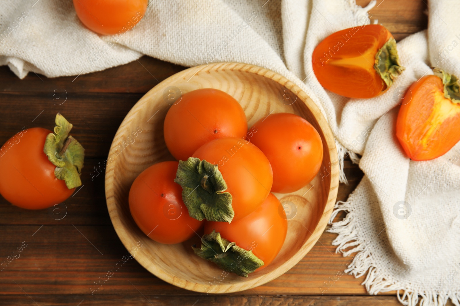 Photo of Tasty ripe persimmons on wooden table, flat lay