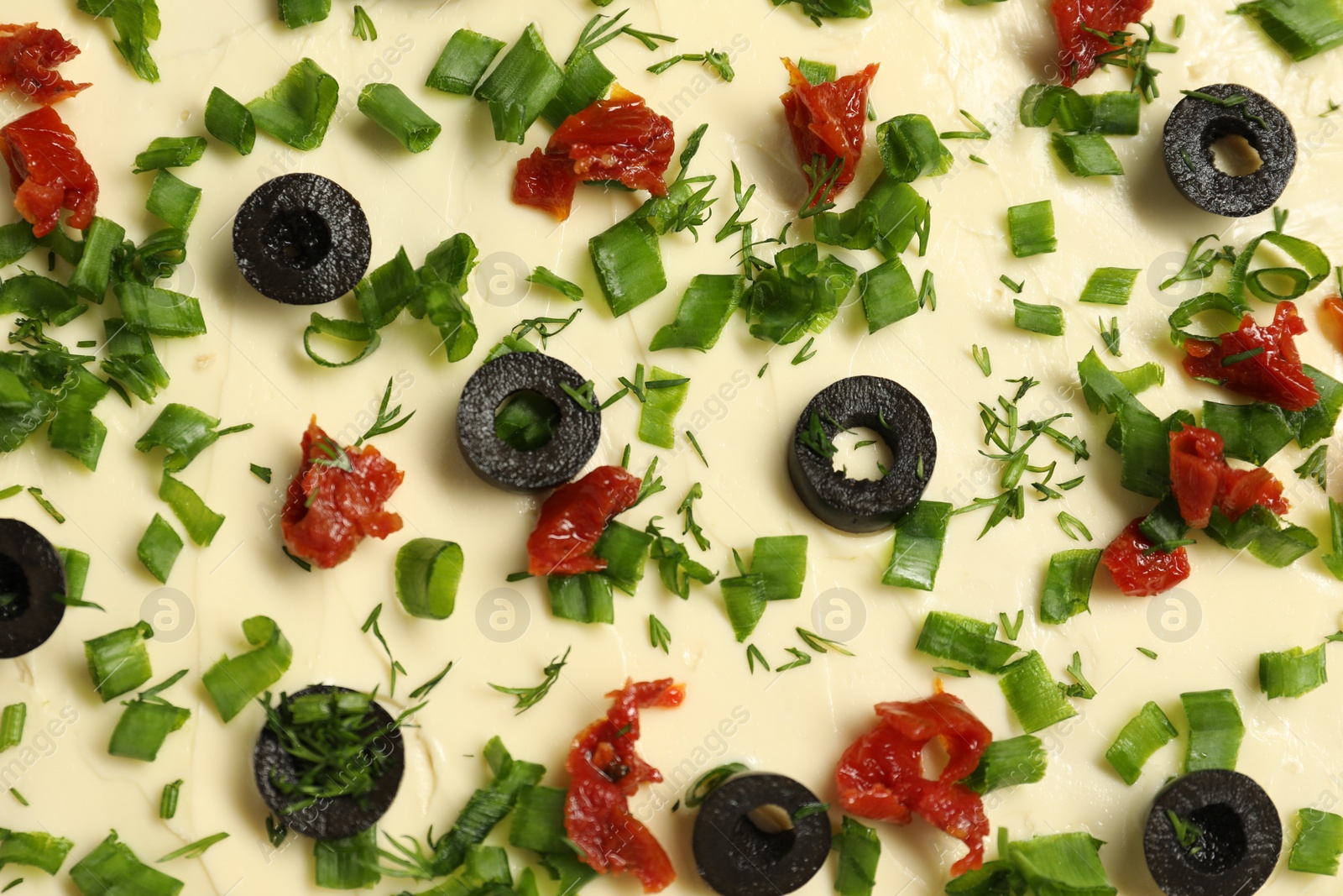 Photo of Fresh natural butter with cut olives, onion and sun-dried tomatoes as background, top view