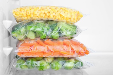 Photo of Plastic bags with deep frozen vegetables in refrigerator