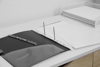 File folder with punched pockets on white table in office