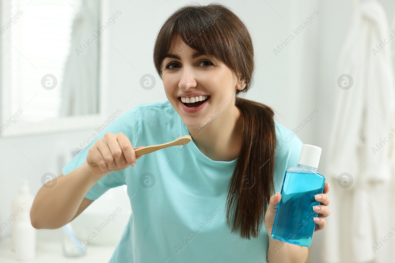 Photo of Young woman with mouthwash and toothbrush in bathroom