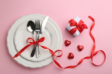 Photo of Beautiful table setting for Valentine's Day dinner on pink background, flat lay