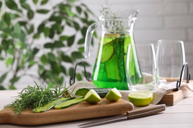 Photo of Fresh homemade refreshing tarragon drink, knife and ingredients on white wooden table, space for text