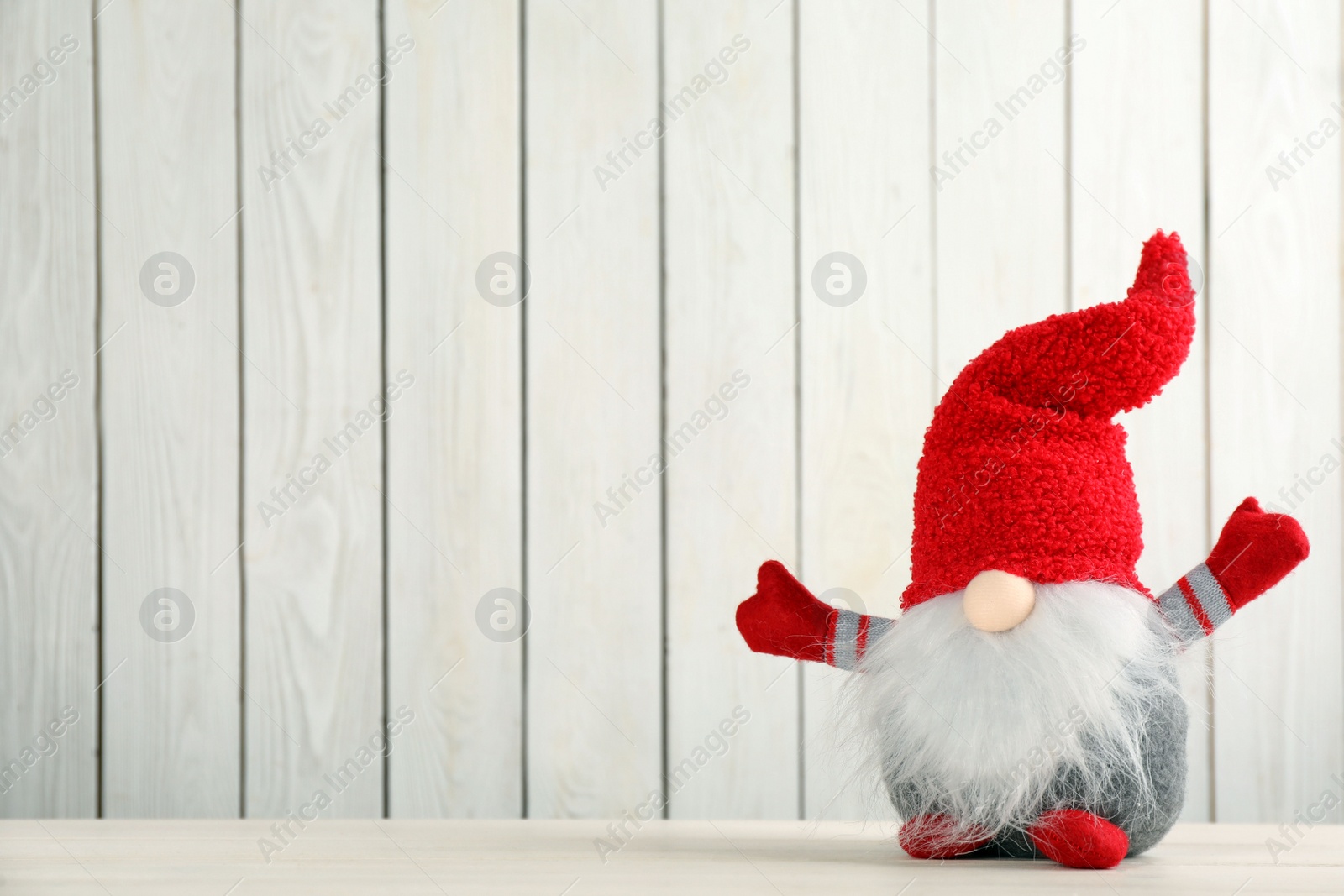 Photo of Cute Christmas gnome on table against white wooden background. Space for text