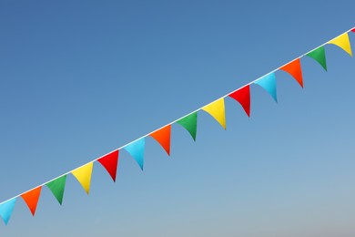 Photo of Bunting with colorful triangular flags against blue sky