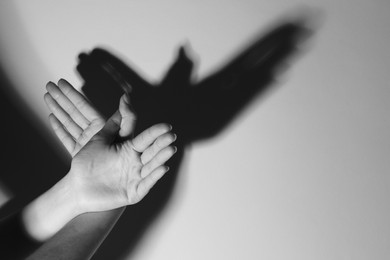 Woman making hand gesture like bird on light background, closeup with space for text. Black and white effect