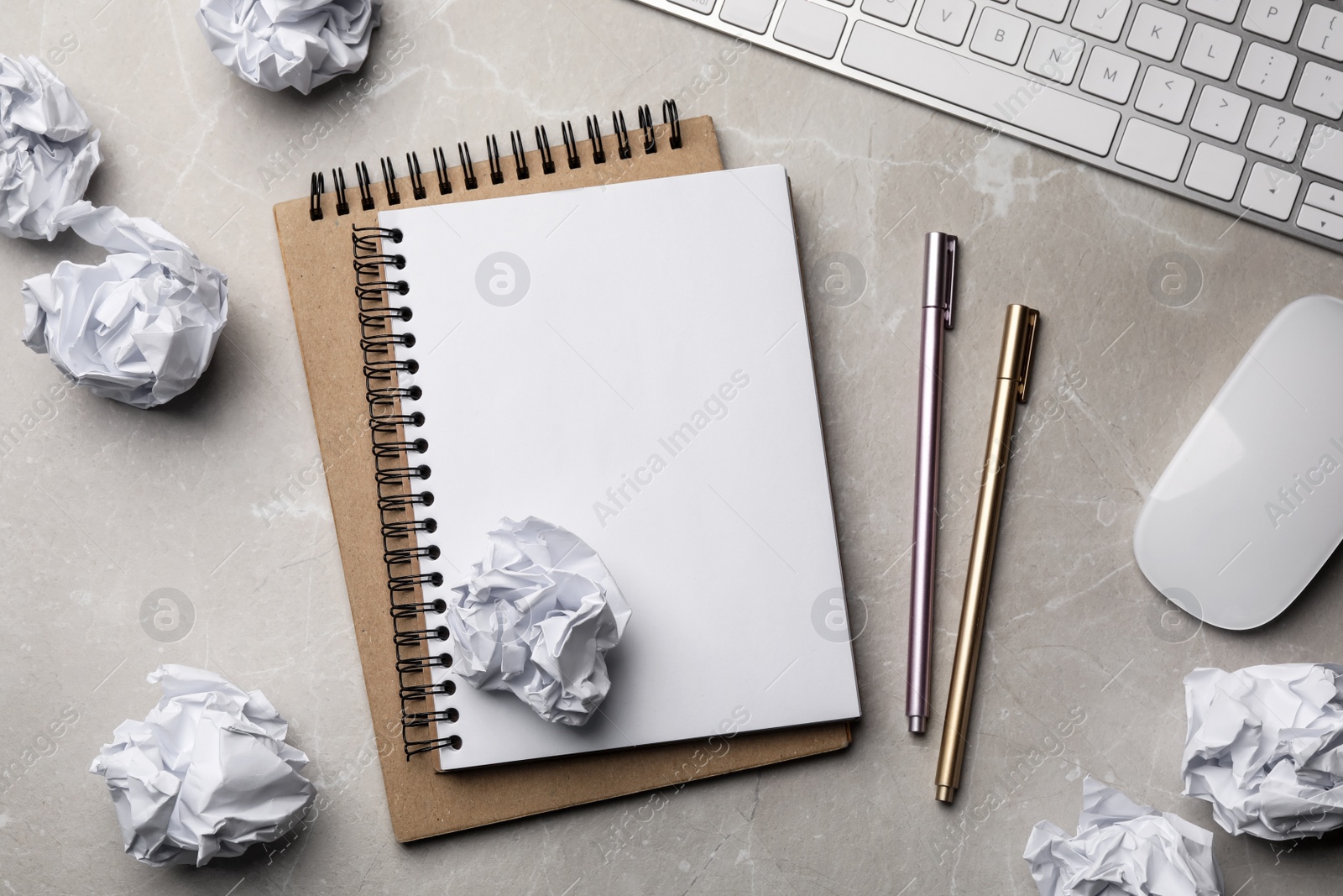 Photo of Flat lay composition with empty notebook and crumpled paper balls on grey marble table. Space for text