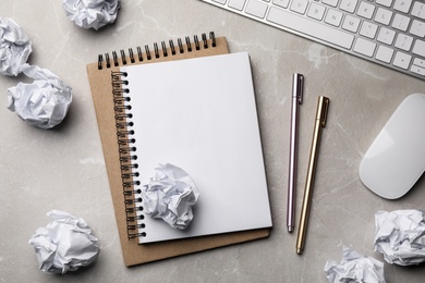 Flat lay composition with empty notebook and crumpled paper balls on grey marble table. Space for text