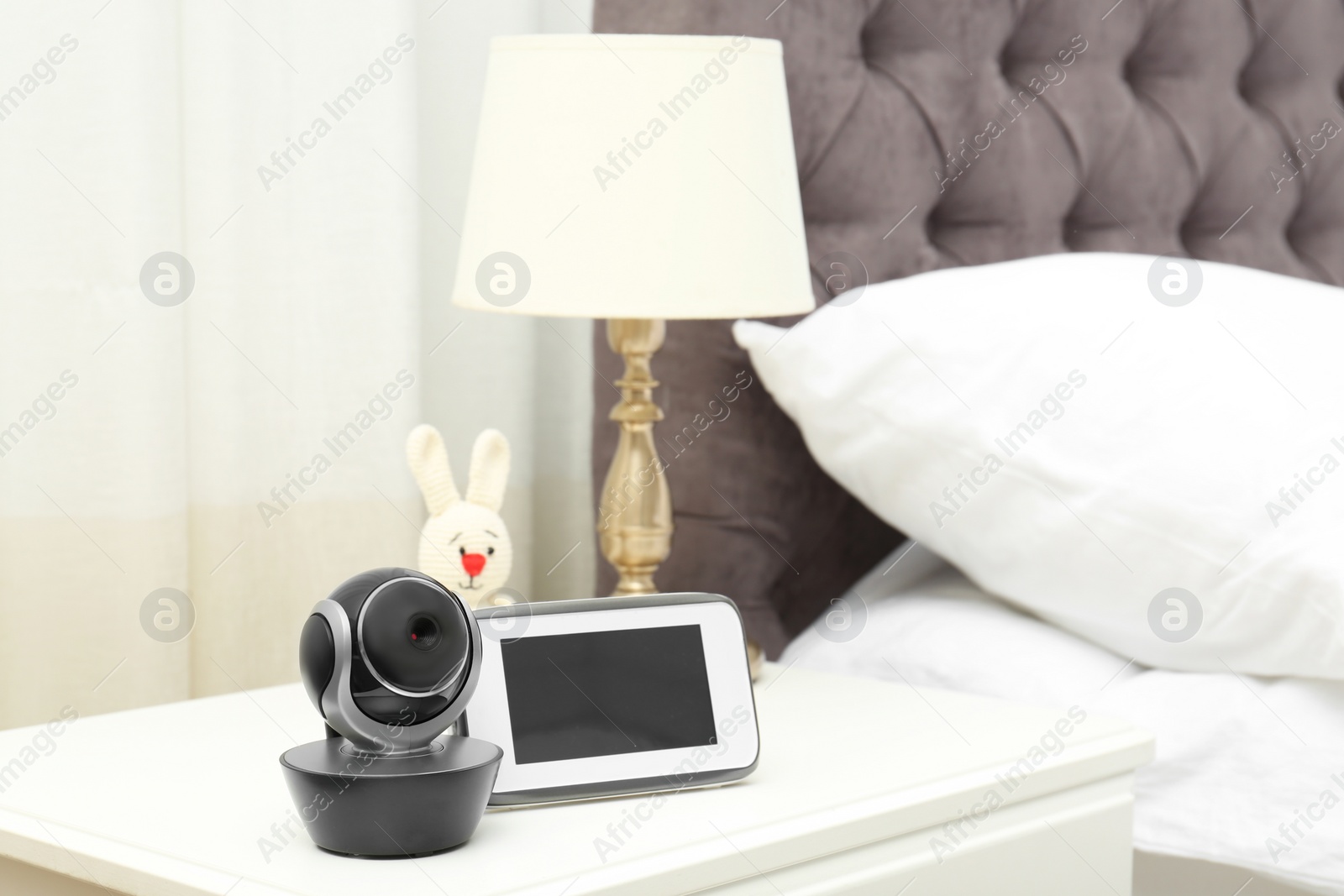 Photo of Baby monitor with camera and toy on table in bedroom, space for text. Video nanny