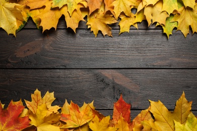Photo of Frame made of autumn leaves on dark wooden table, flat lay. Space for text