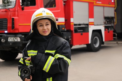 Photo of Firefighter in uniform with high pressure water jet near fire truck outdoors