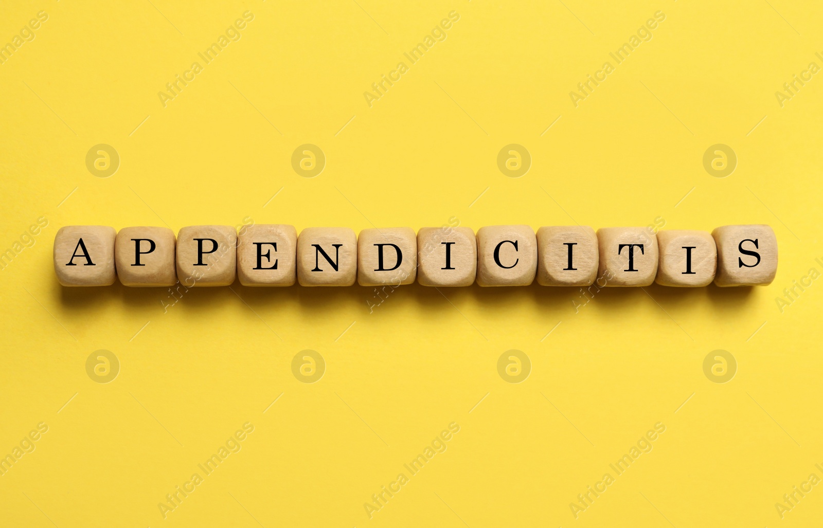 Photo of Word Appendicitis made of wooden cubes with letters on yellow background, top view