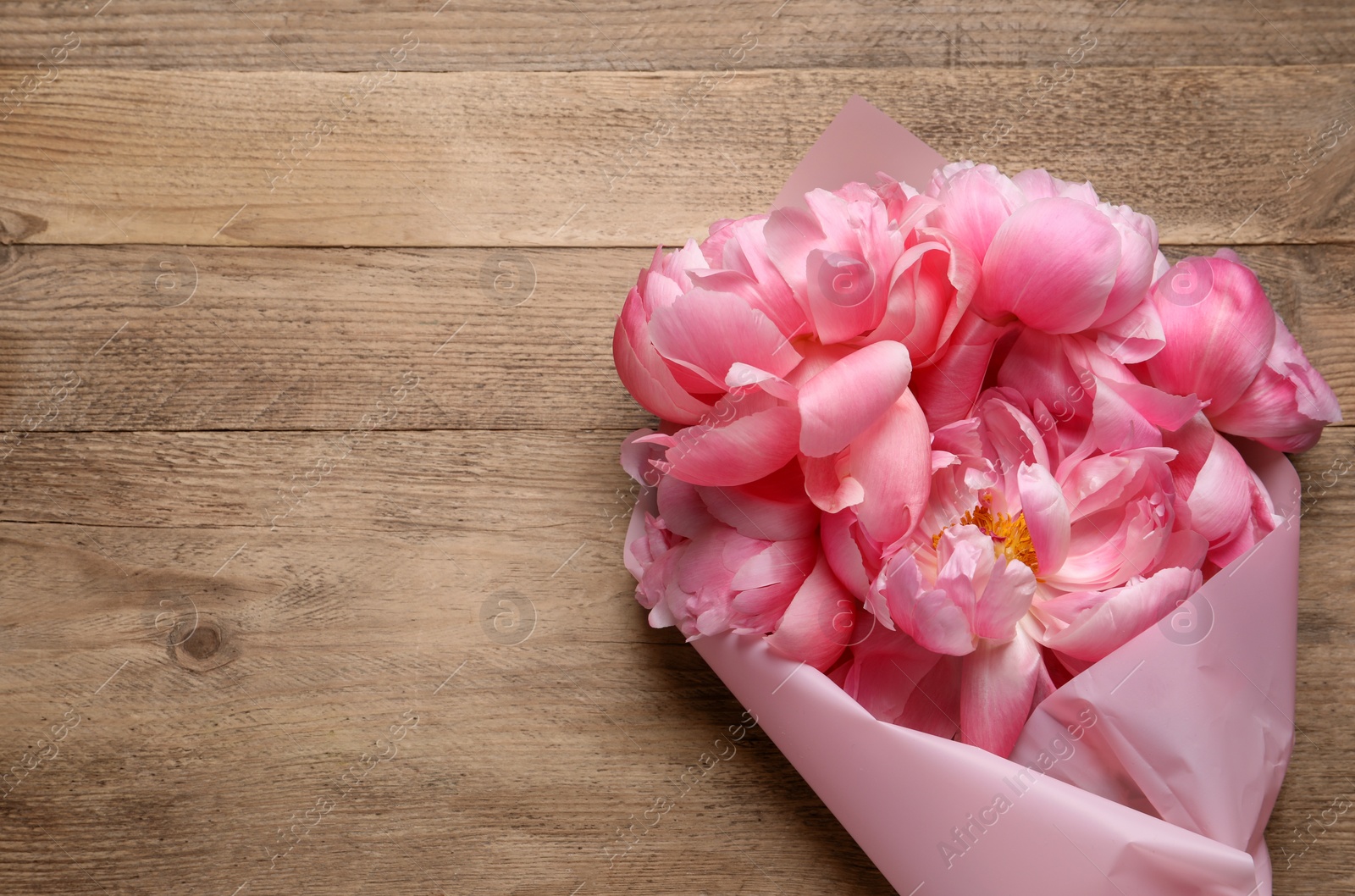 Photo of Beautiful bouquet of pink peonies on wooden table, top view. Space for text