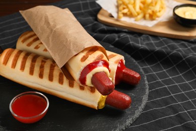Photo of Delicious french hot dogs, fries and dip sauce on table, closeup