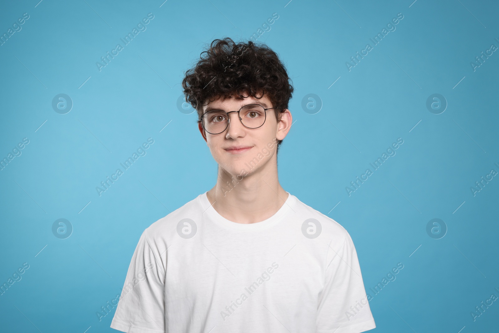 Photo of Portrait of cute teenage boy wearing glasses on light blue background