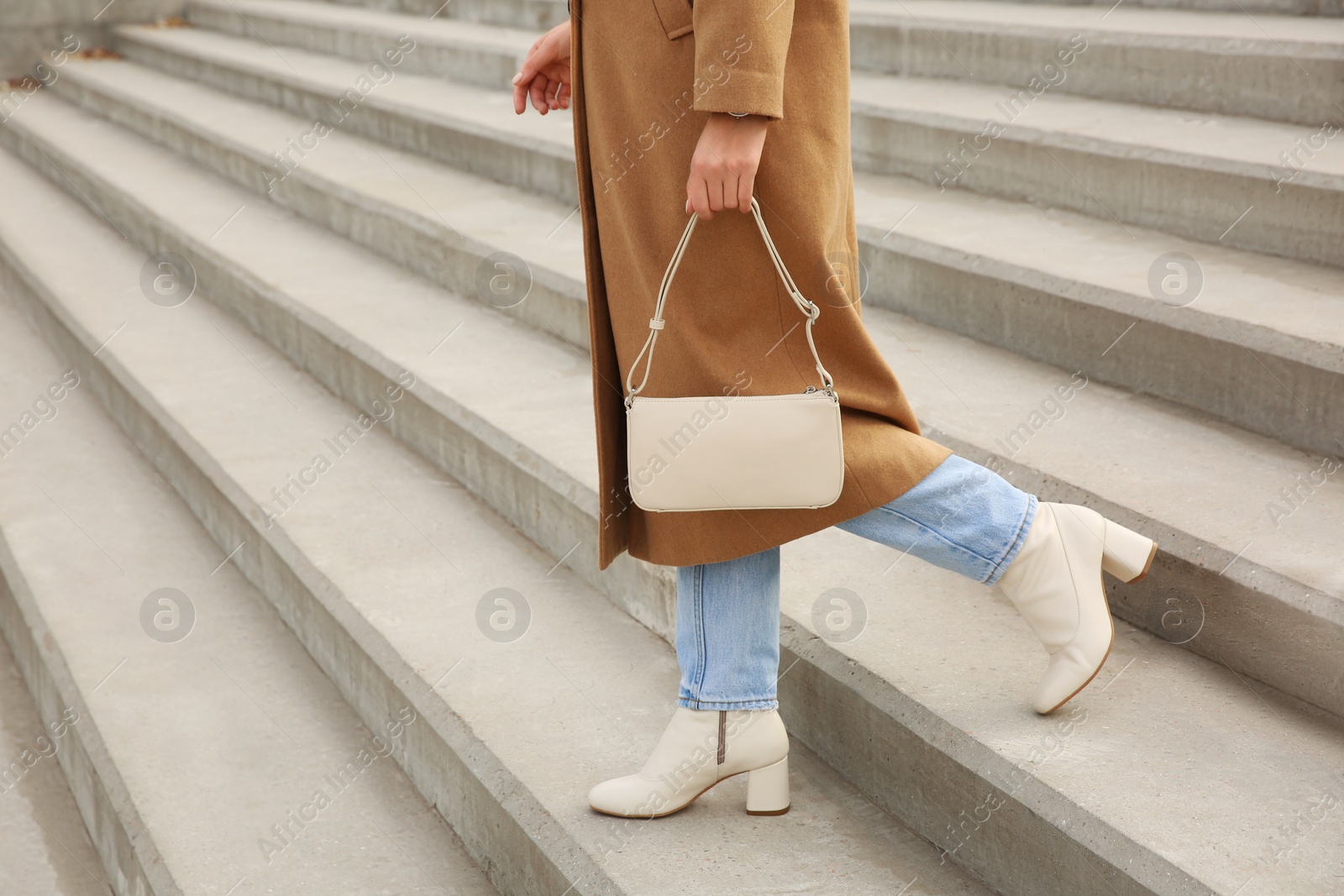 Photo of Stylish woman with trendy beige bag on stairs outdoors, closeup