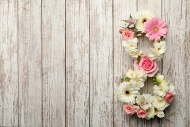 Photo of Number 8 made of beautiful flowers on white wooden table, flat lay with space for text. International Women's day