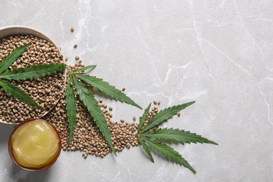 Photo of Bowl of hemp lotion and space for text on gray background, flat lay