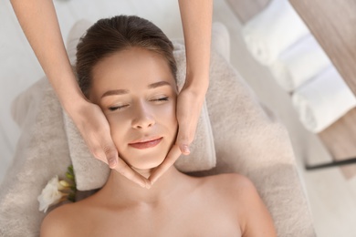 Young woman enjoying face massage in spa salon