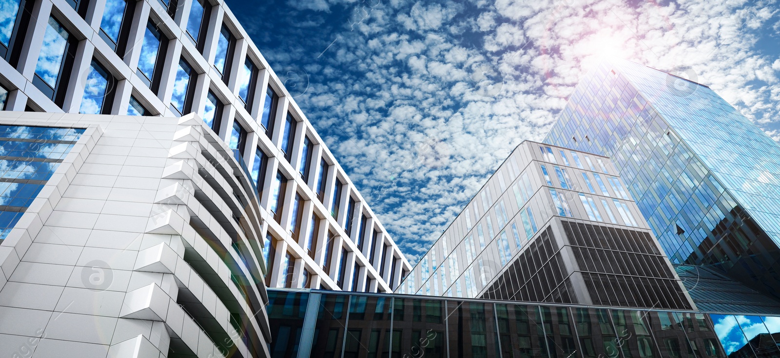 Image of Beautiful blue sky with clouds reflecting in windows, banner design. Low angle view of modern buildings on sunny day