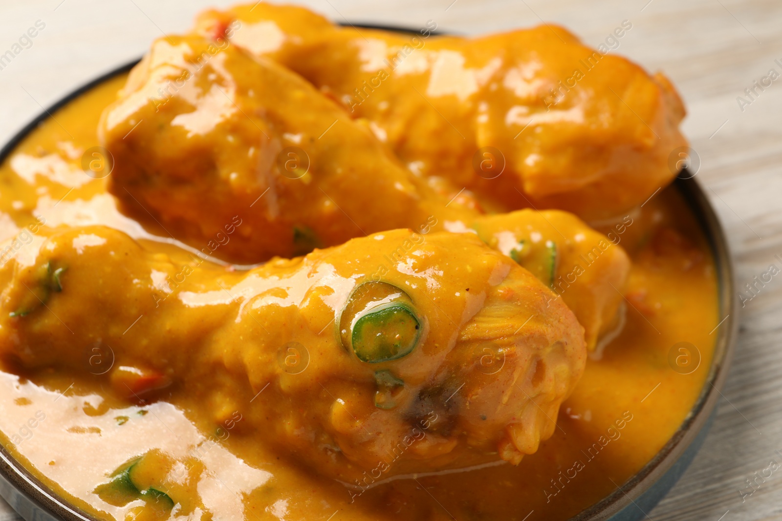 Photo of Tasty chicken curry on wooden table, closeup