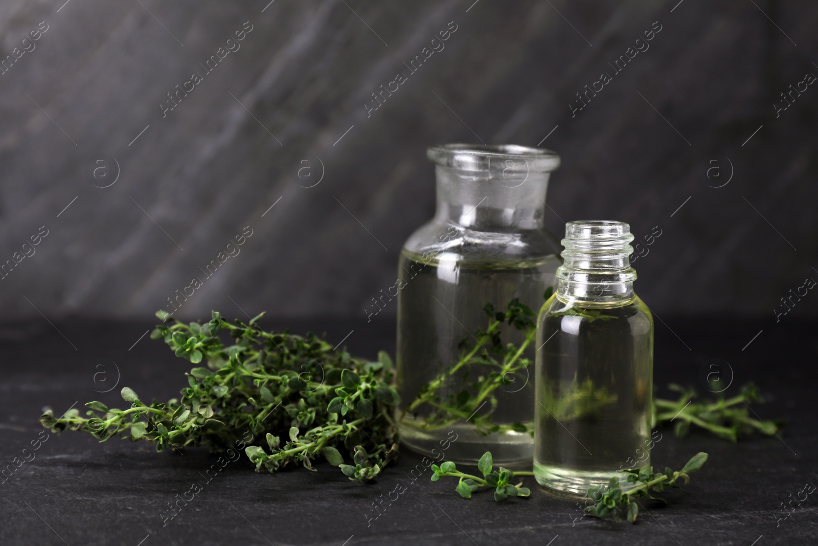 Photo of Natural thyme essential oil on black table