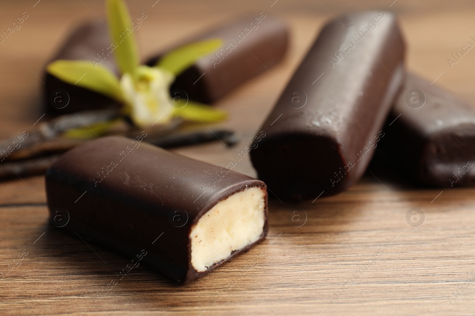 Photo of Glazed vanilla curd cheese bars on wooden table, closeup