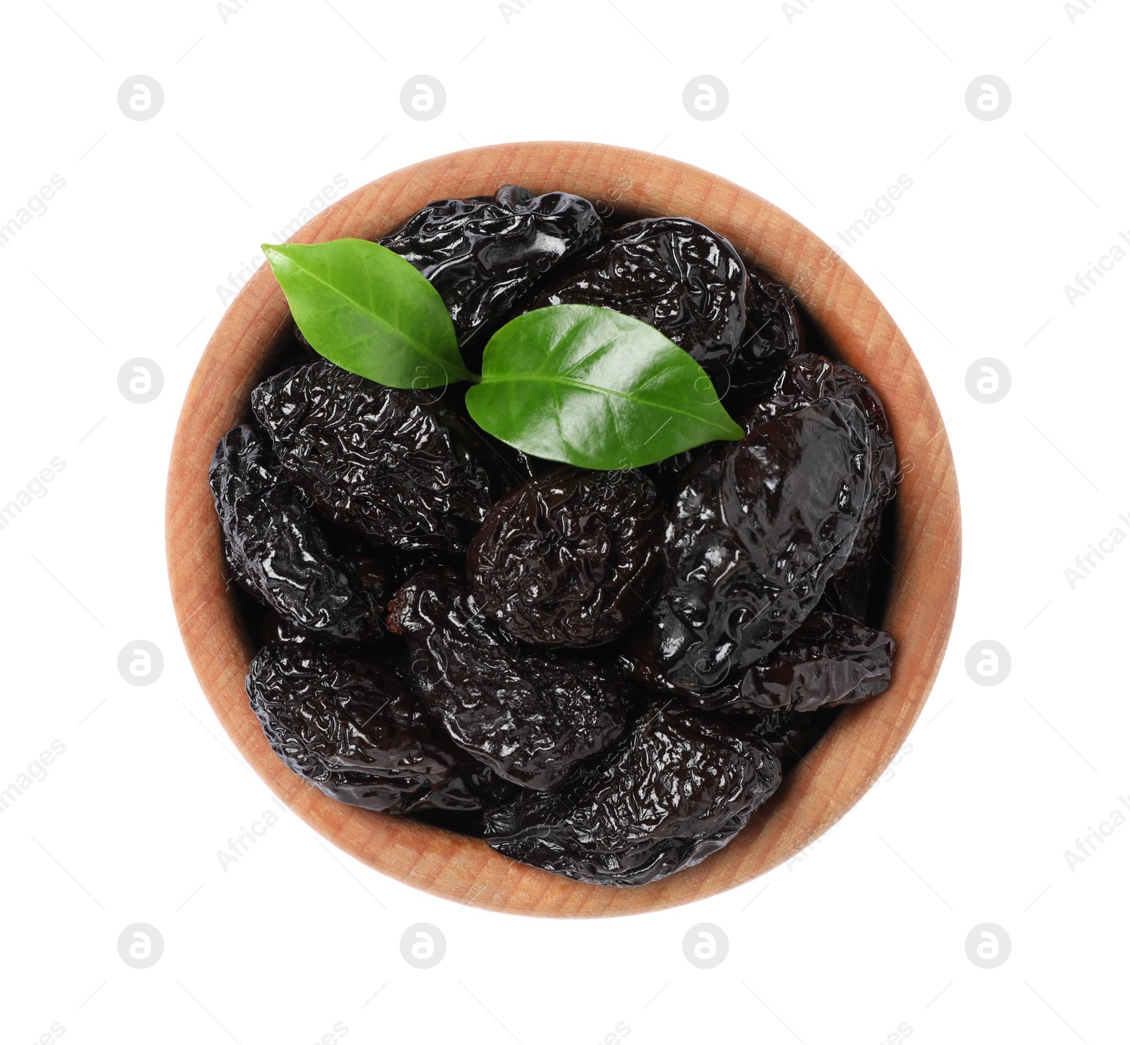 Photo of Wooden bowl with sweet dried prunes and green leaves isolated on white, top view