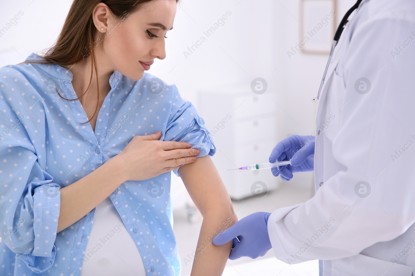 Photo of Doctor giving injection to pregnant woman in hospital. Vaccination concept