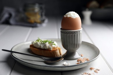 Photo of Fresh soft boiled egg in cup and sandwich on white wooden table