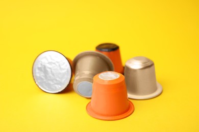 Photo of Many plastic coffee capsules on yellow background, closeup