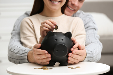Photo of Couple with piggy bank at white table, closeup