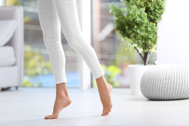 Photo of Woman walking barefoot at home, space for text. Floor heating