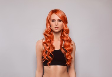 Beautiful woman with long orange hair on light grey background