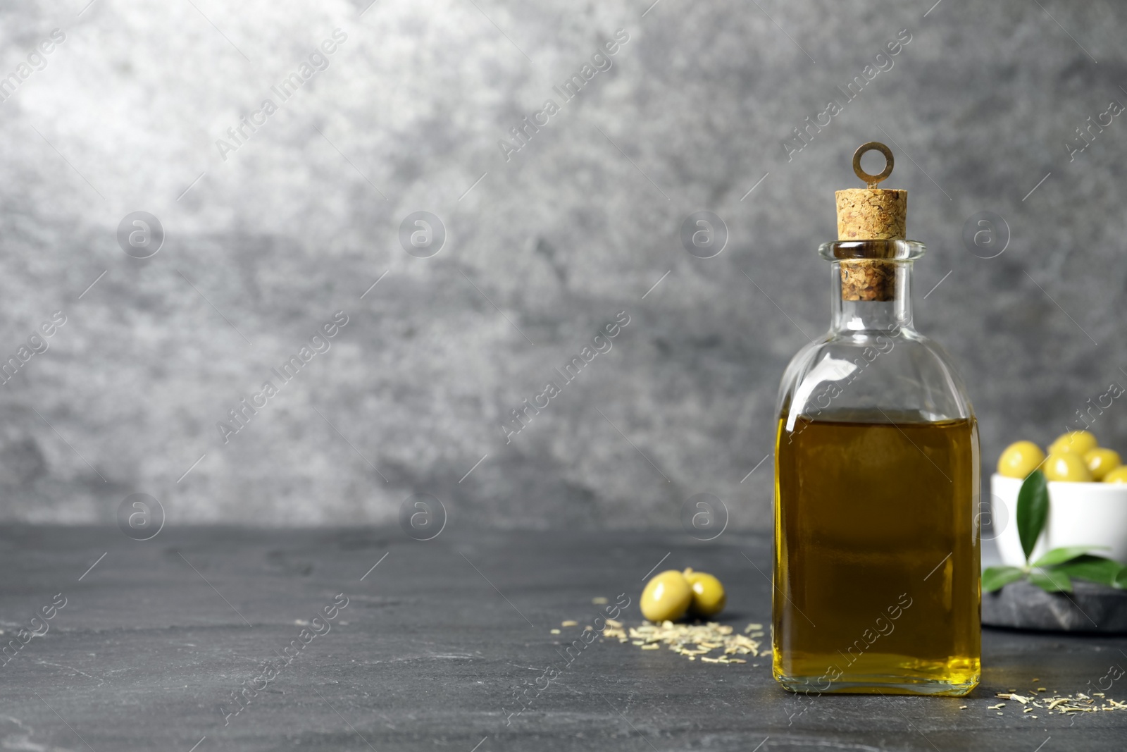 Photo of Bottle of fresh olive oil on dark grey table, space for text