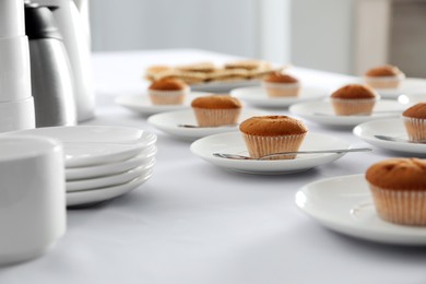 Photo of Many delicious muffins served on white table for coffee break