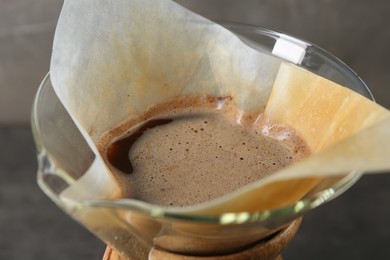Paper filter with aromatic drip coffee in glass chemex coffeemaker, closeup