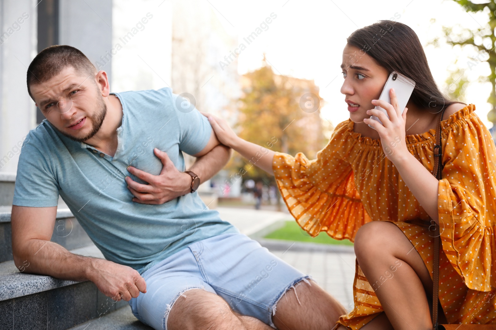 Photo of Woman calling ambulance to help man with heart attack on stairs