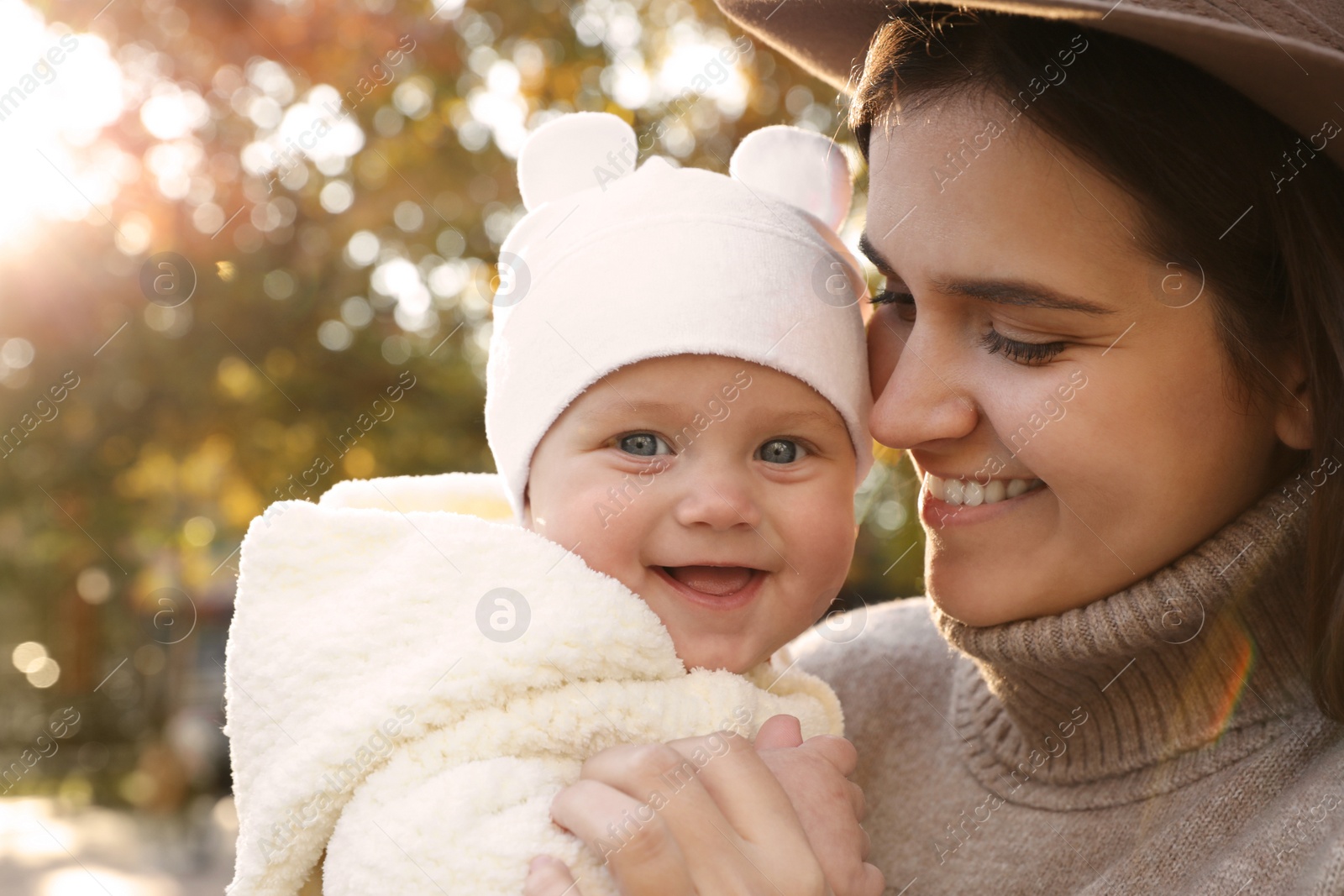 Photo of Happy mother with her baby daughter outdoors on autumn day, closeup