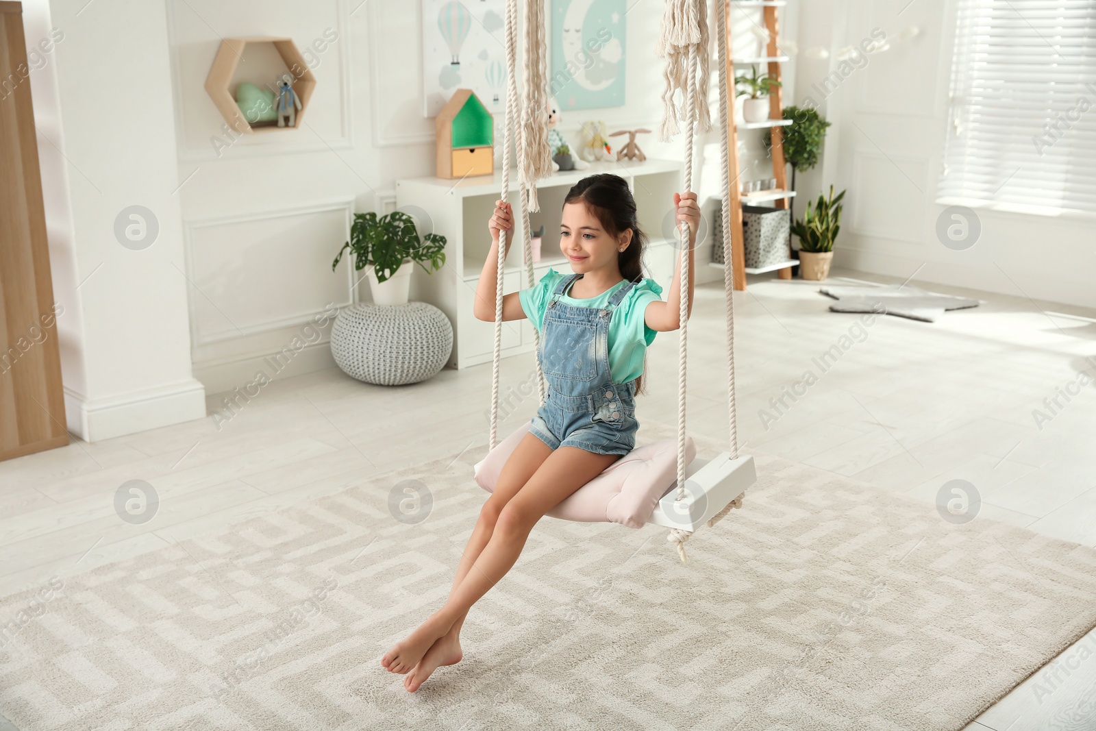 Photo of Cute little girl playing on swing at home