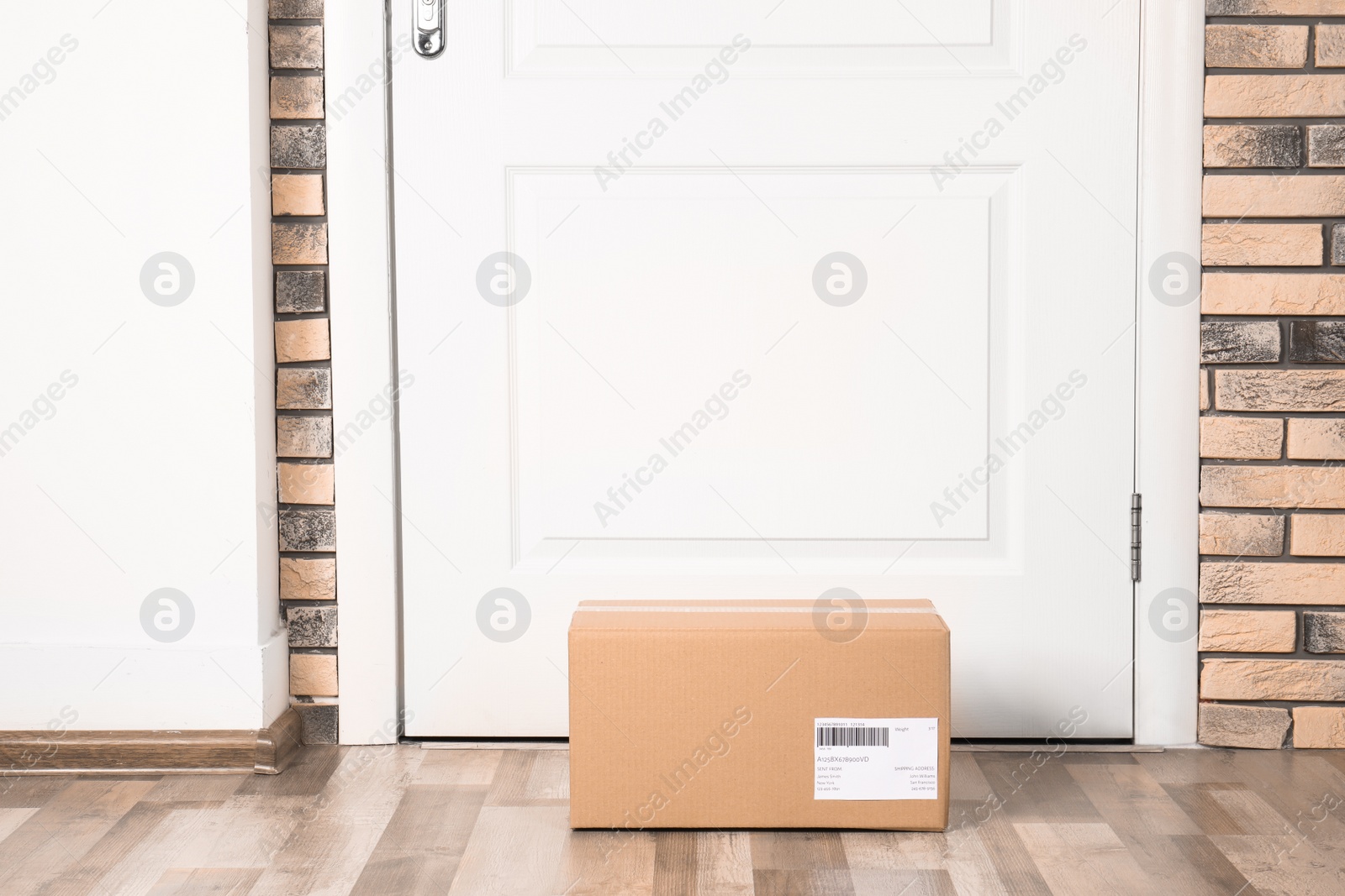 Photo of Cardboard parcel box on floor near apartment entrance. Mockup for design