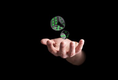 Man throwing dice on black background, closeup