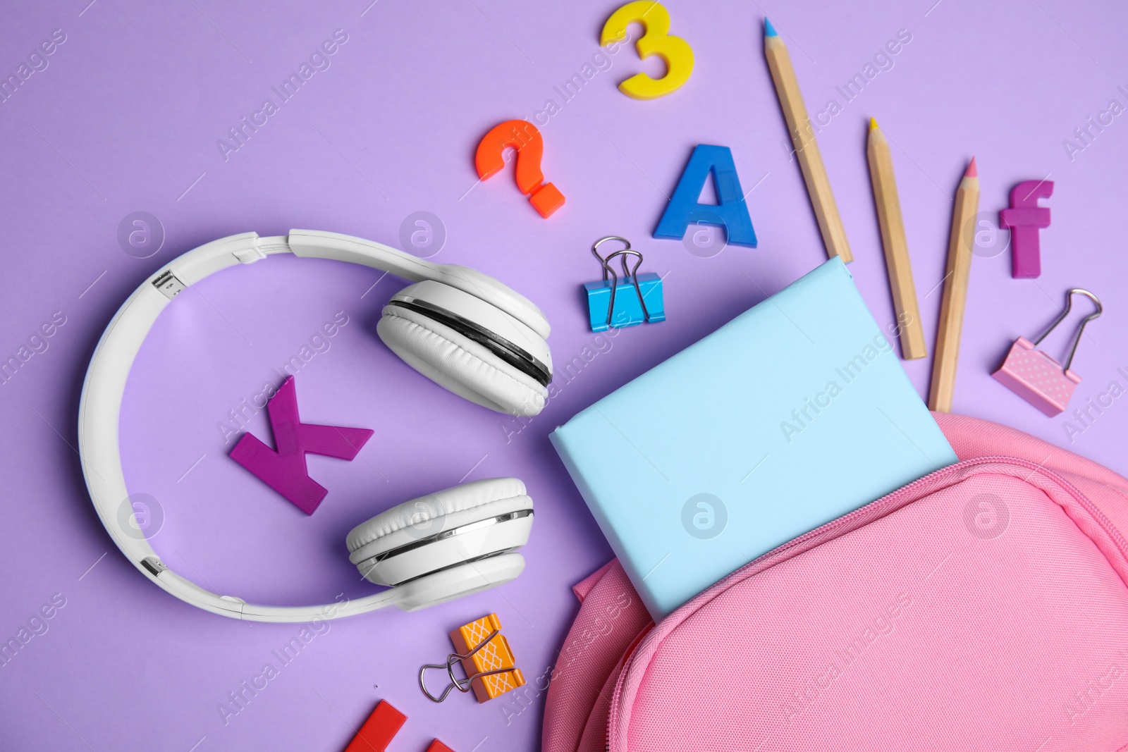 Photo of Flat lay composition with book and headphones on lilac background