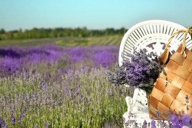 Photo of Wicker bag with beautiful lavender flowers on chair in field, space for text